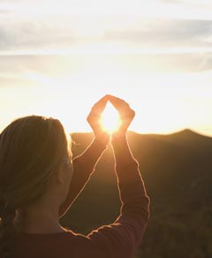 woman cupping hands around sunlight