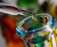 Colourful close-up of a glass pipette dropping liquid into a test tube