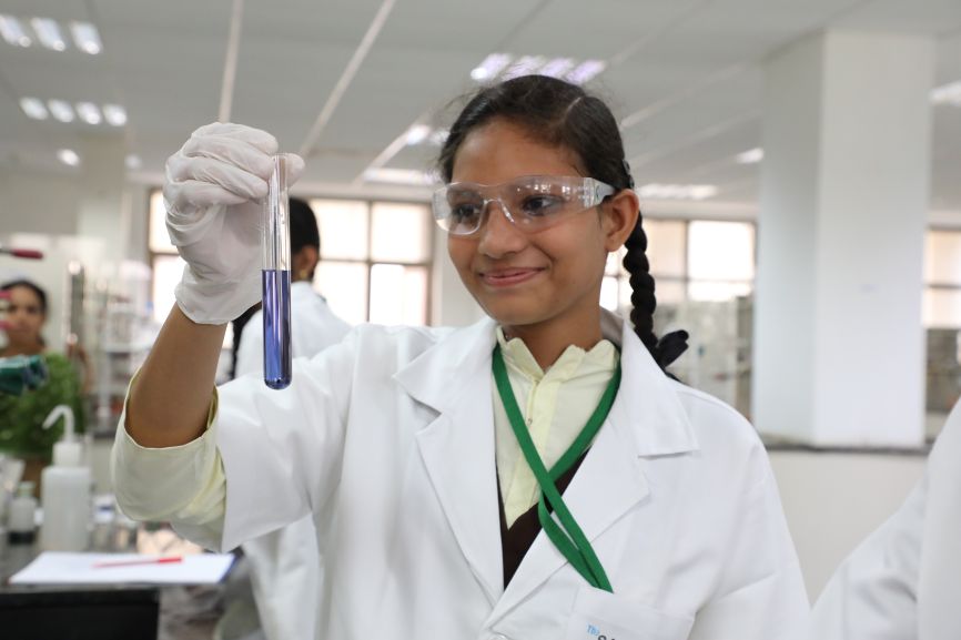 A smiling young girl holds up a test tube A smiling young girl holds up a test tube