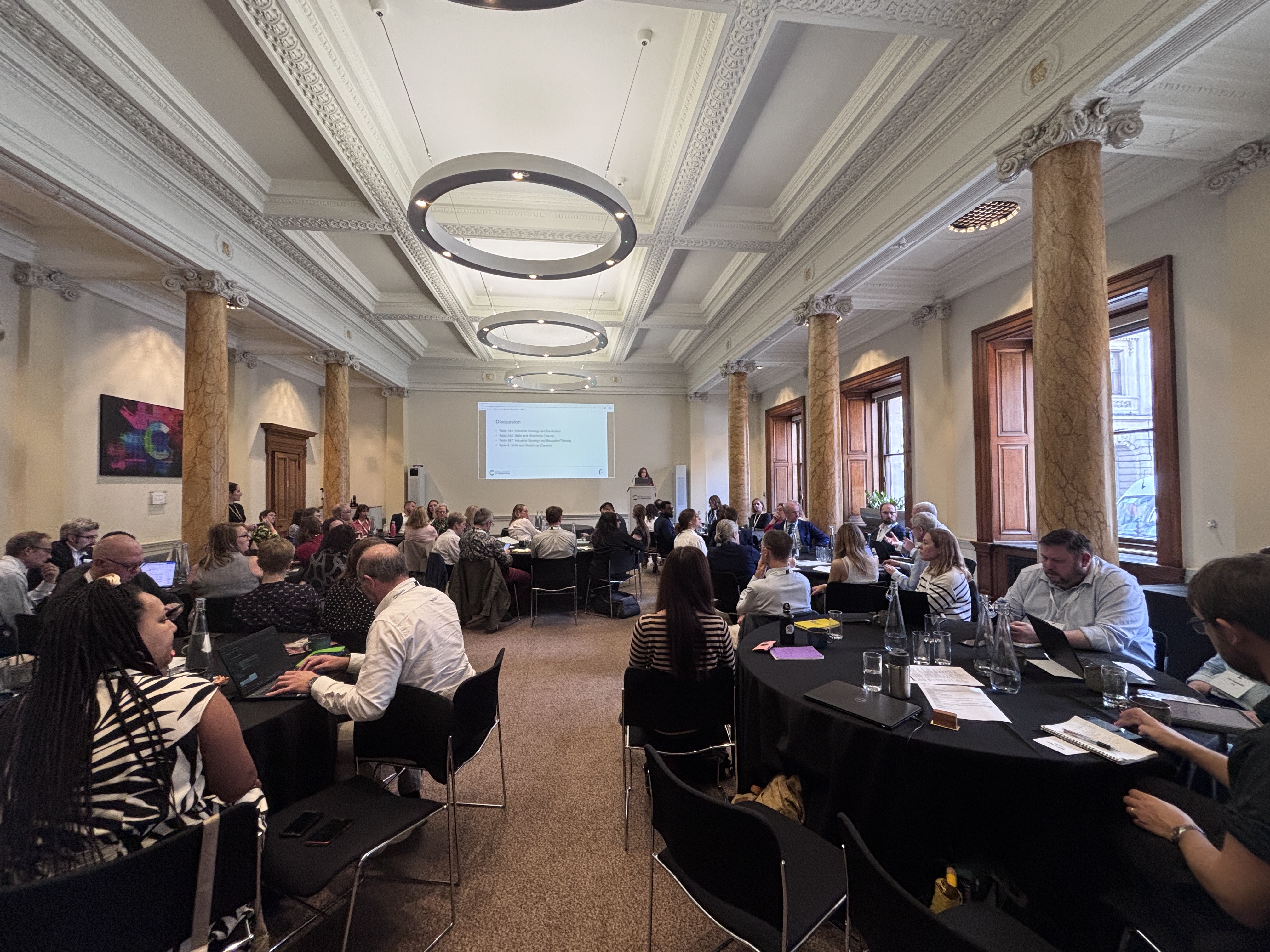 a group of people sitting at tables in a room with columns