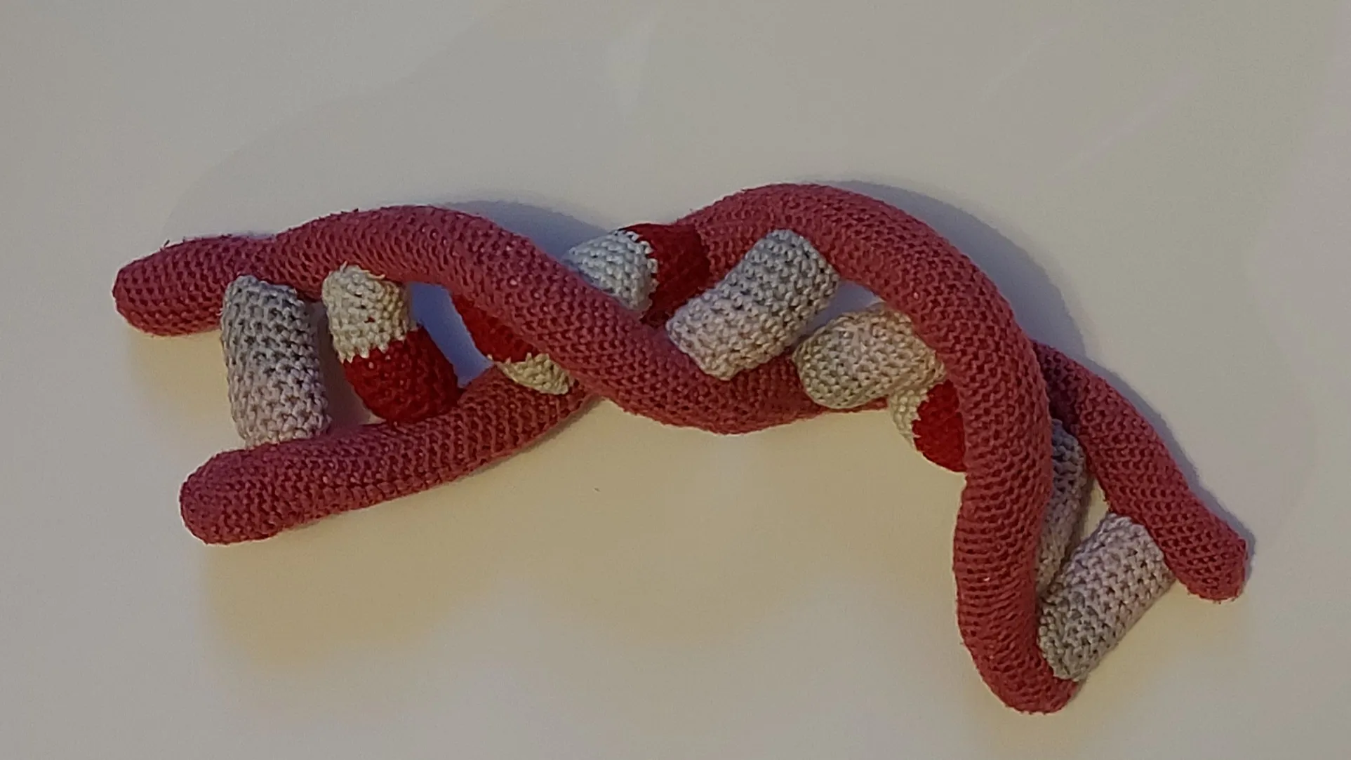 a knitted chain of DNA in red and grey
