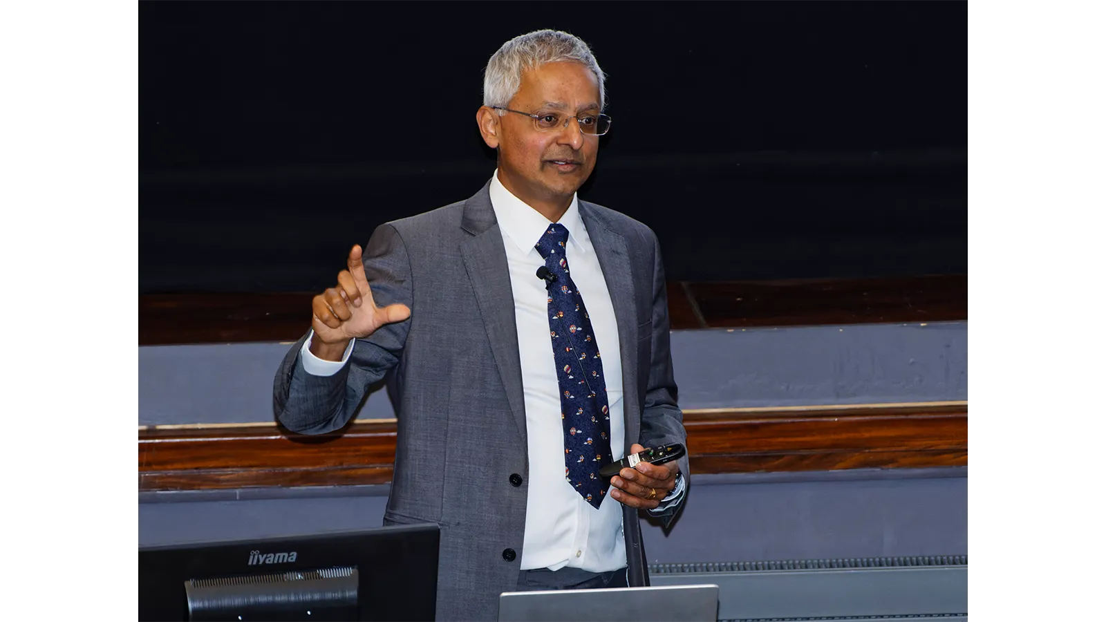 Professor Sir Shankar Balasubramanian in a suit and tie delivering a seminar