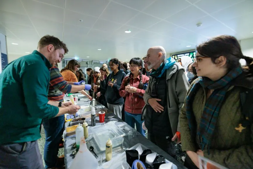 A man speaks with visitors to the Bitesized Soft Matter stand at the Imperial Lates event