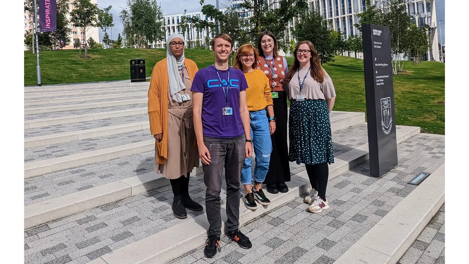 Dr Rebecca Beveridge with team members standing on outside steps smiling to camera