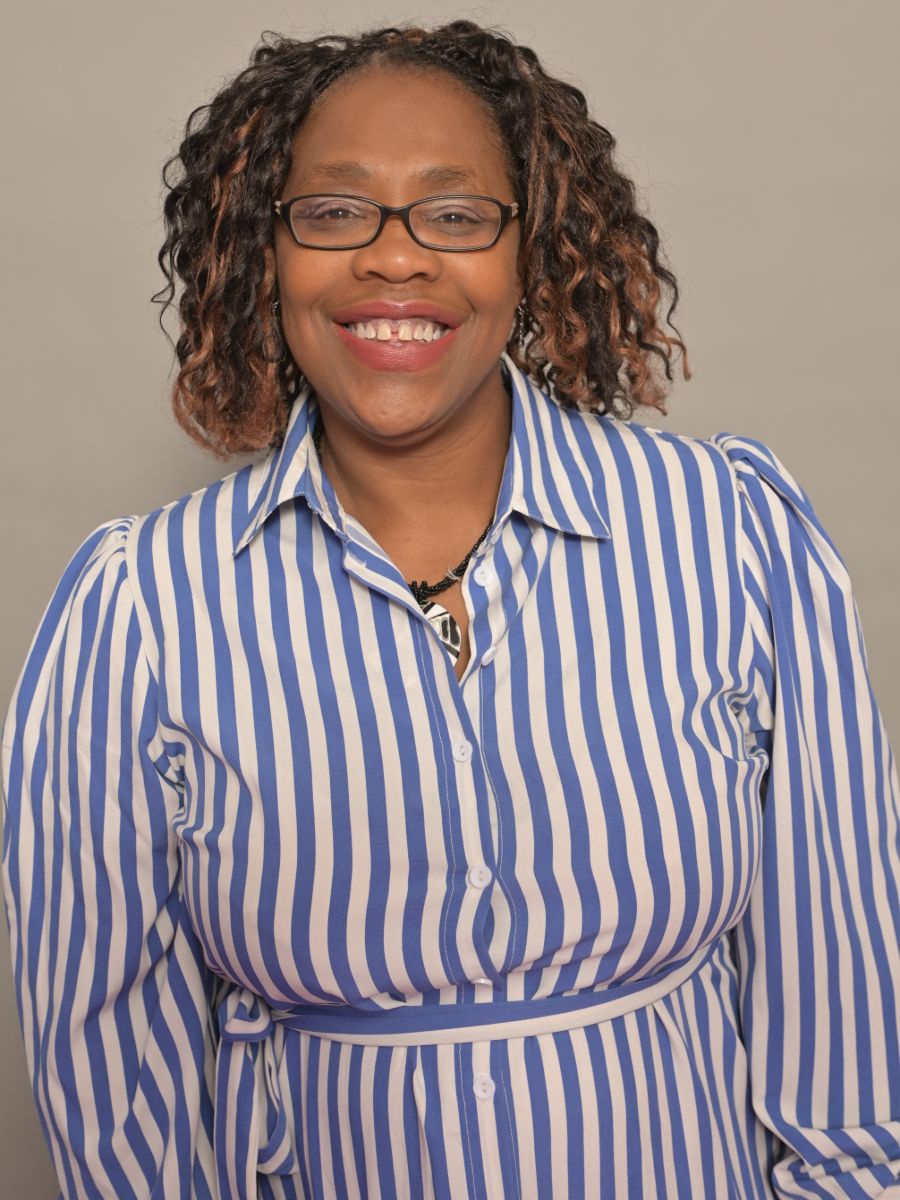Marcia Philbin smiling at camera wearing glasses and a striped shirt