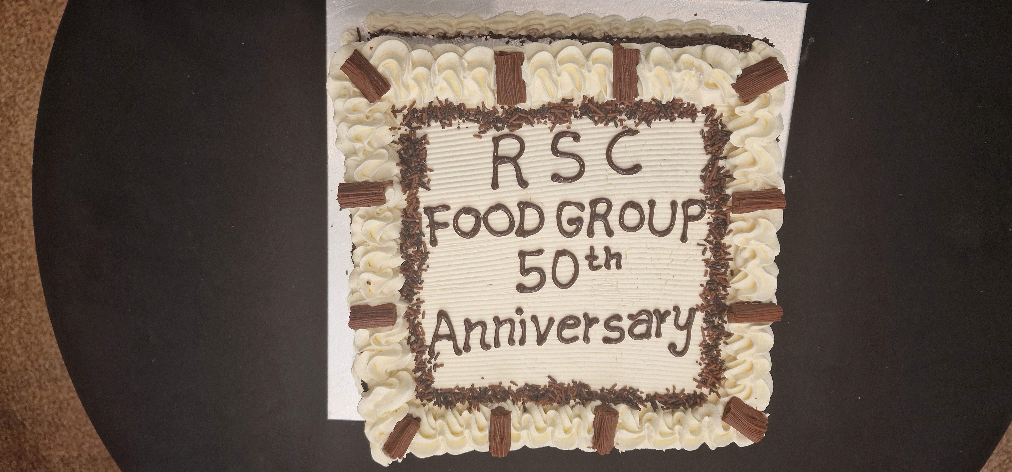 A special cake that has "RSC Food Group 50th Anniversary" written on the top in chocolate icing.