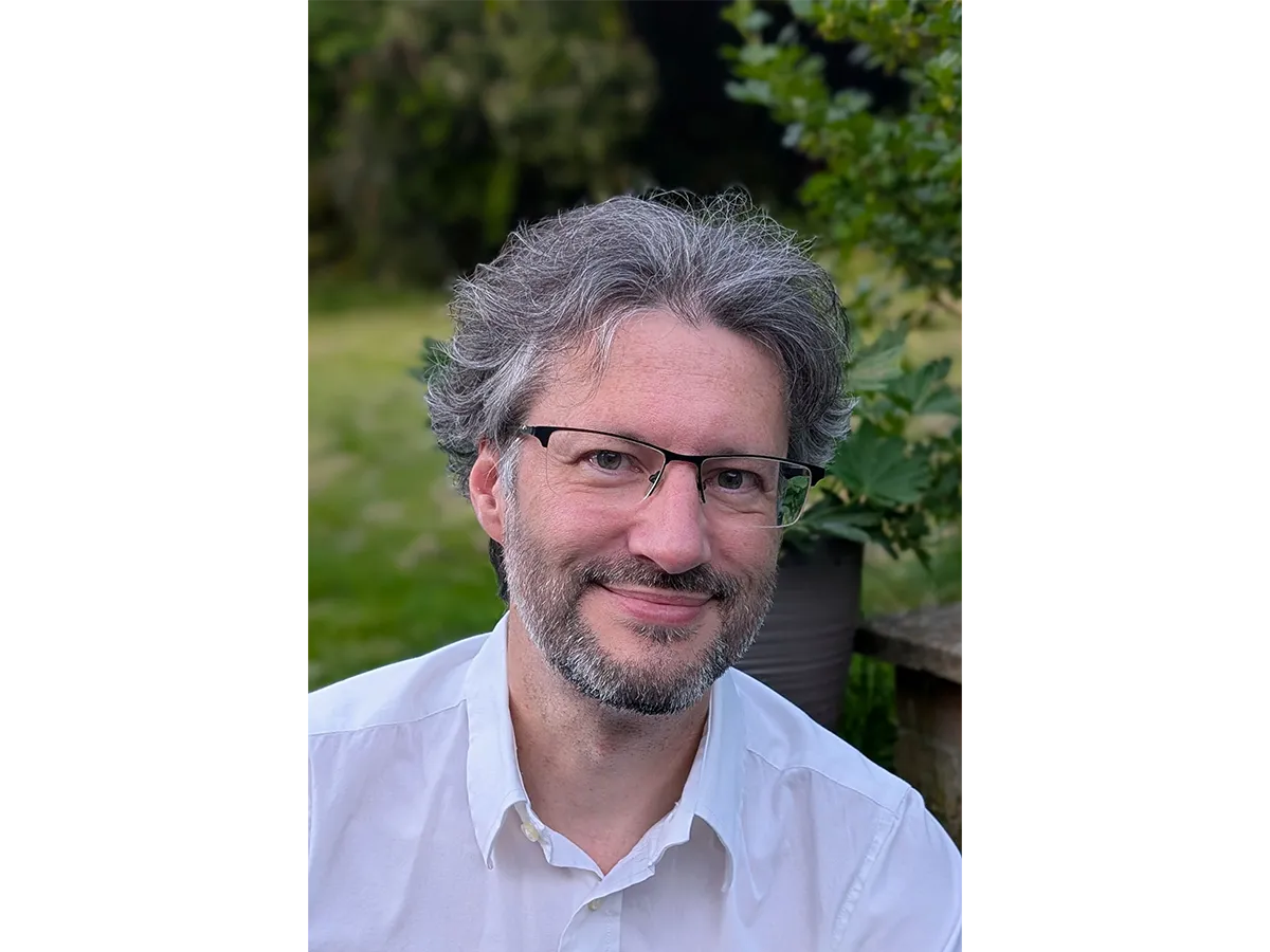 Professor Igor Larrosa wearing white shirt and glasses smiling for camera