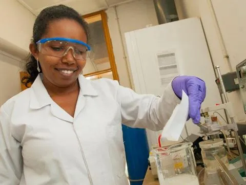 Smiling female scientist in a lab holding a note in hand