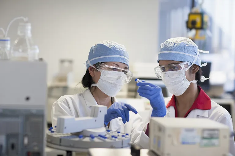 A technician shows a young scientist how to use some equipment