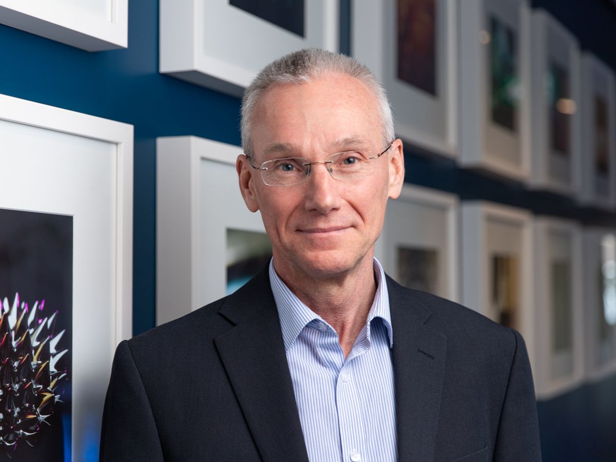 Rick Russell headshot smiling to camera wearing suit and glasses